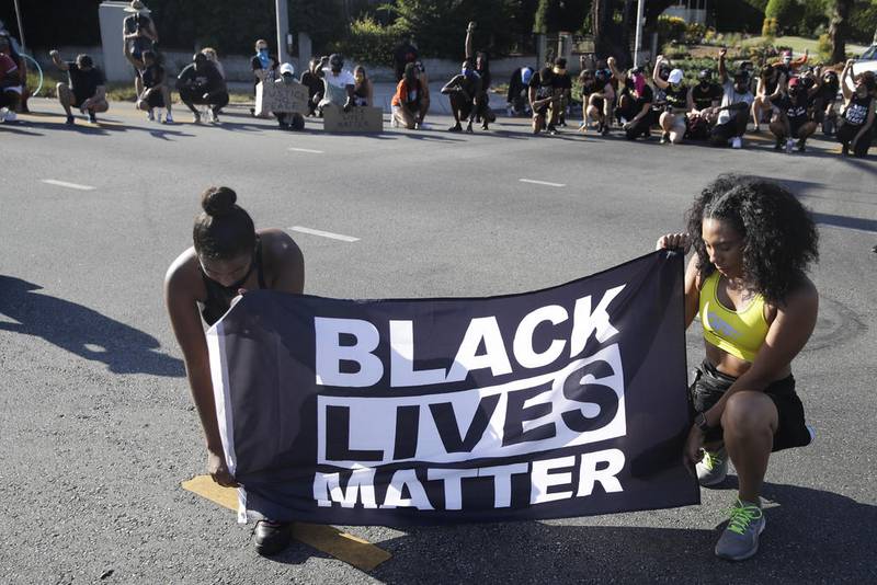 FILE - In this July 11, 2020 file photo, Alycia Pascual-Pena, left, and Marley Ralph kneel while holding a Black Lives Matter banner during a protest in memory of Breonna Taylor, in Los Angeles. Taylor was killed in her apartment by members of the Louisville, Ky., Metro Police Department on March 13. The International Law Enforcement Educators and Trainers Association, a prominent law enforcement training group, is promoting a lengthy research document riddled with falsehoods and conspiracies that urges local police to treat Black Lives Matter activists as terrorists plotting a violent revolution. The document contains misinformation and inflammatory rhetoric that could incite officers against protesters and people of color, critics said. (AP Photo/Marcio Jose Sanchez, File)