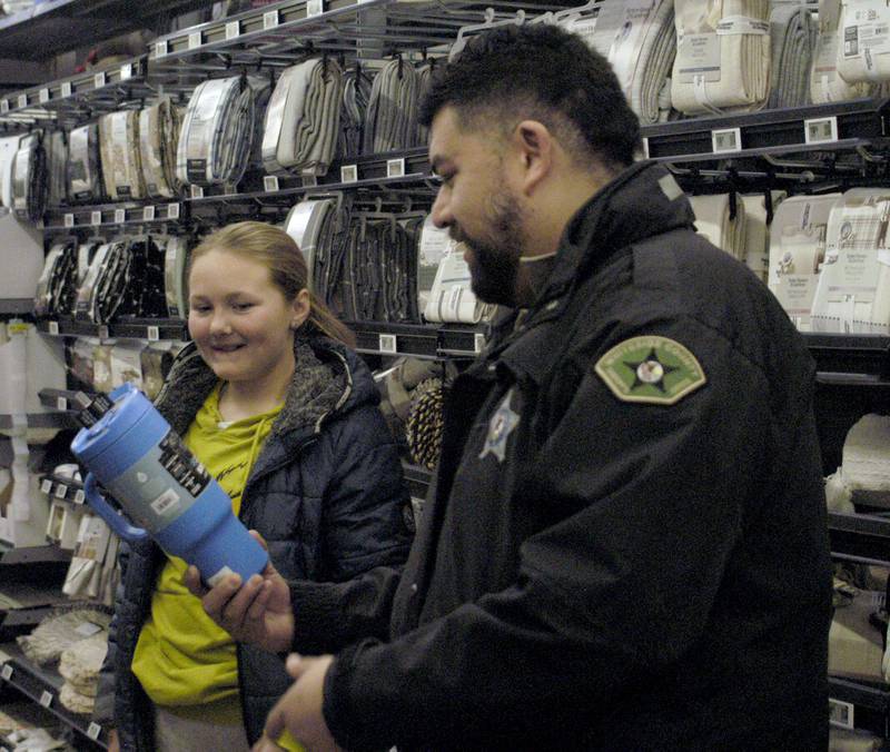 Ralleigh Holloway and Deputy Eduardo Reyes look over a gift Saturday, Dec. 13, 2025, at Sterling Walmart.