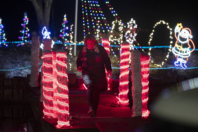 Peggy Peugh crosses a lighted bridge Tuesday, Nov. 26, 2024, at Centennial Park in Rock Falls. Peugh was decorating the bridge and islands for Halo.