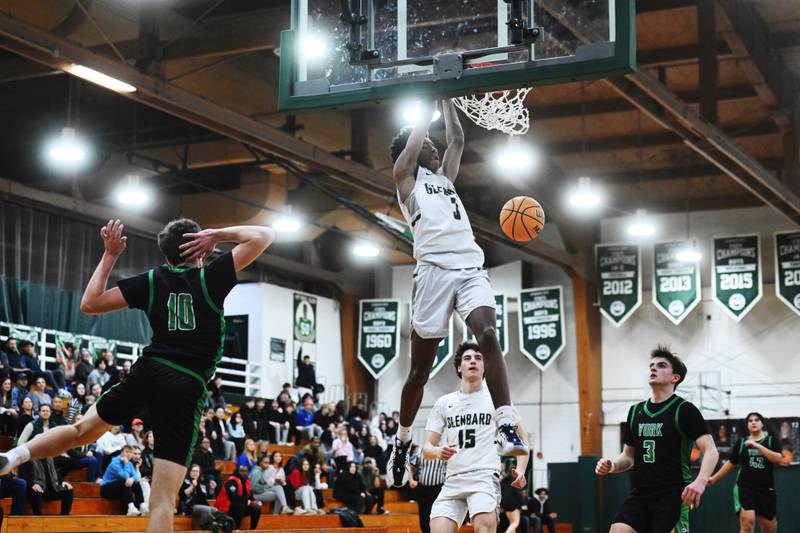 York's Brendan Carroll, left, can't stop a dunk by Glenbard West's TJ Williams as Drew Gacek (15) and Connor Fitzgerald (3) arrive at the end of the play during Friday's game in Glen Ellyn.