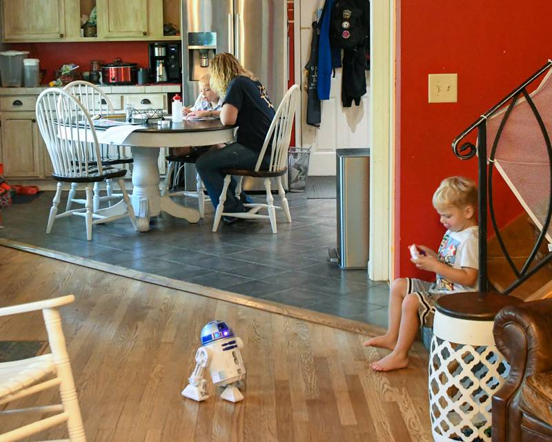 Brooke Christenson watches her son Malcom, 5, trace different continents while home schooling her kids on Friday Oct. 3, 2025, in St. Charles Township while her other son Maverick, 3, plays with a remote R2D2.