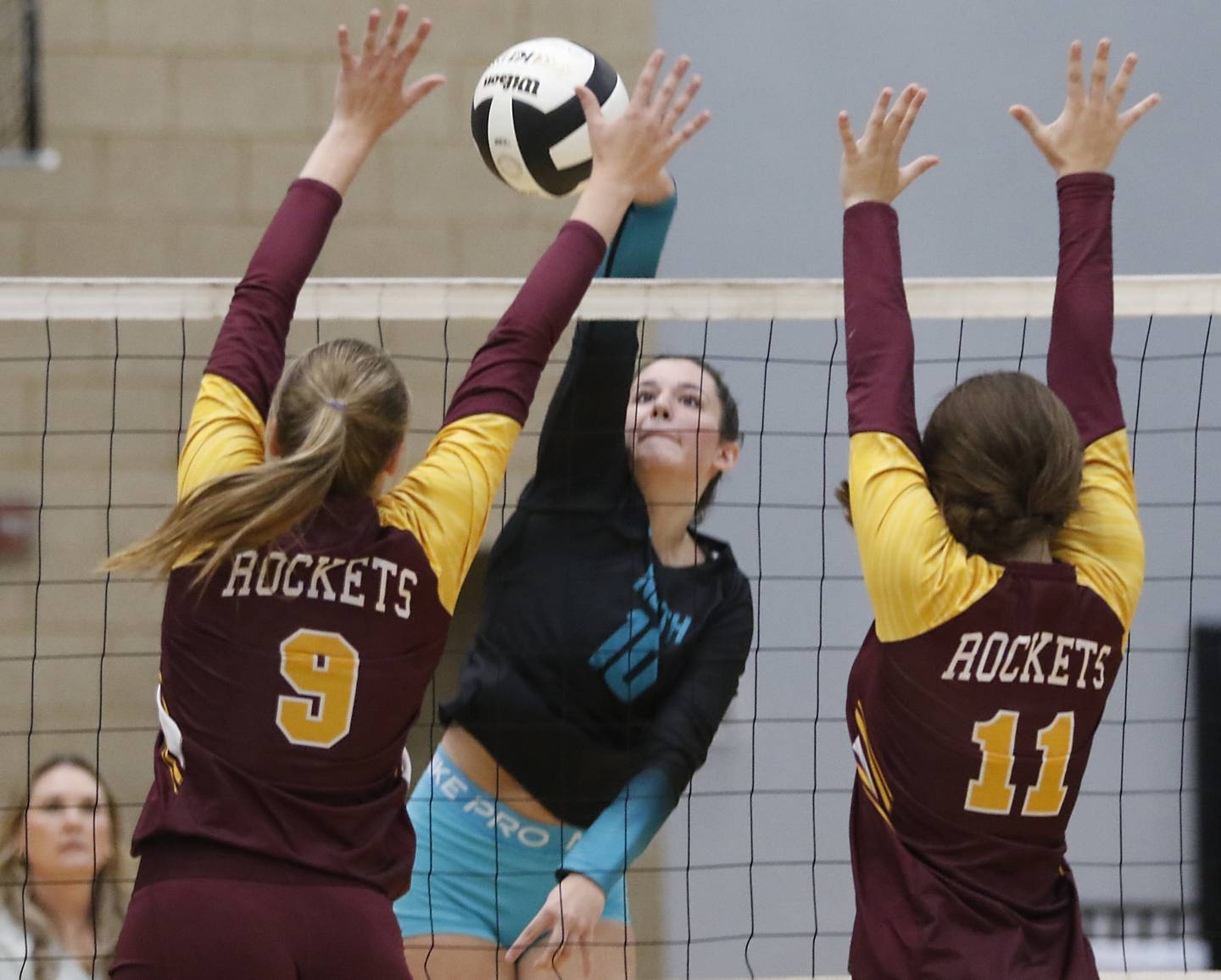 Woodstock North's Ava Kardaras (center) hits the ball between Richmond-Burton's Reagan Wisniewski (left) and Mia Furlan (right) during a Kishwaukee River Conference volleyball match on Monday, Sept. 15, 2025, at the Woodstock North High School.