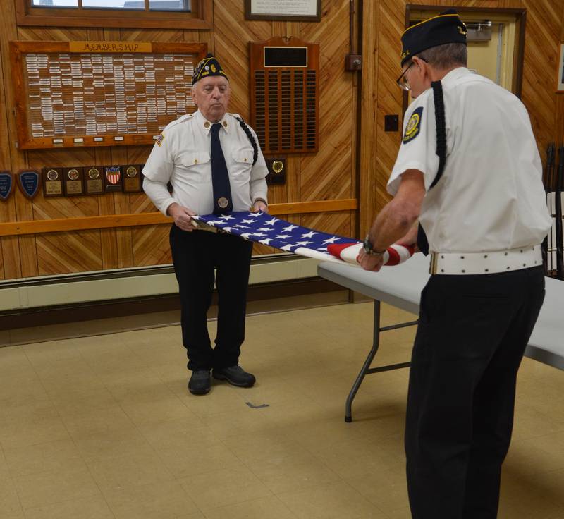 James Seidel (left) and Robert Bartel fold an American flag at the Sterling American Legion Post on Sunday during a Pearl Harbor remembrance ceremony.