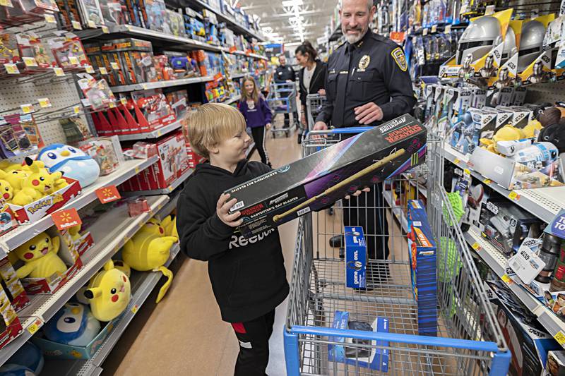 Ace Parker, 8, adds a gift to the cart pushed by Dixon police chief Steve Howell Saturday, Dec. 9, 2023. Each participant had $150 to spend for Christmas.