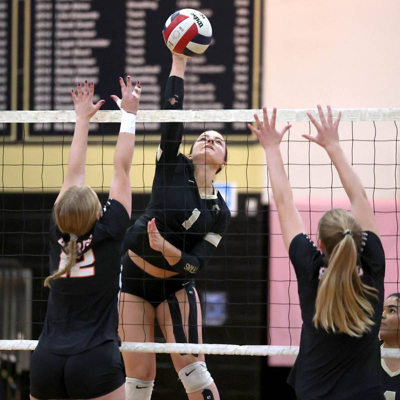 Sycamore's Grace Lichardt tries to spike the ball between two DeKalb blockers during their match Monday, Oct. 16, 2023, at Sycamore High School.