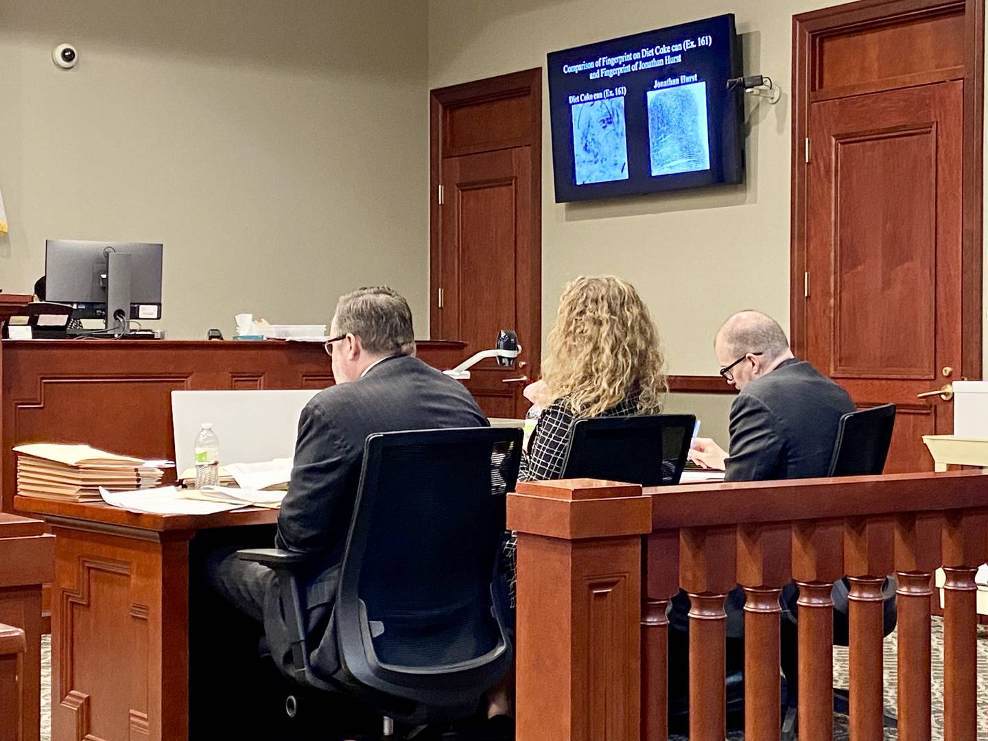 An enlarged police forensic photograph of a fingerprint found on a Diet Coke can inside Patricia and Robert Wilson's Sycamore home in August 2016 is shown next to an enlarged picture of Jonathan D. Hurst's fingerprint during Hurst's criminal trial on Tuesday, Jan. 26, 2025. Hurst (right) sits taking notes with his defense attorneys, Chip Criswell (left) and Emma Franklin. He was charged with murder after the Wilsons were found beaten to death inside their home on Aug. 15, 2016. A police forensic expert testified that the two fingerprints match.