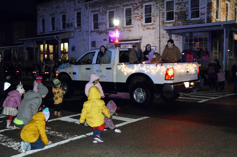 Kids run for candy thrown from a decorated pickup truck holding members of Pine Creek Valley 4-H participating in the Polo Christmas Festival's first ever Parade of Lights on Saturday, Dec. 2, 2023.
