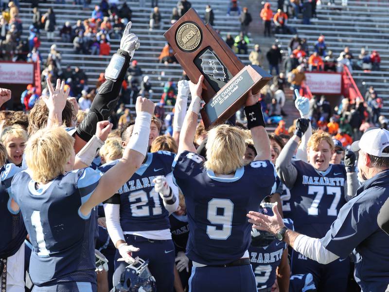 Nazareth's Brendan Flanagan brings the state championship trophy to his team Saturday, Nov. 25, 2023, after their IHSA Class 5A state championship win over Joliet Catholic Hancock Stadium at Illinois State University in Normal.