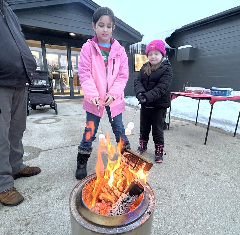 Baylee Dunseth, 9, of Davis, and Astrid Griggs, 7, of Polo, roast marshmallows to make smores at First State Bank during the Polo Christmas Festival on Saturday, Dec. 6, 2025.