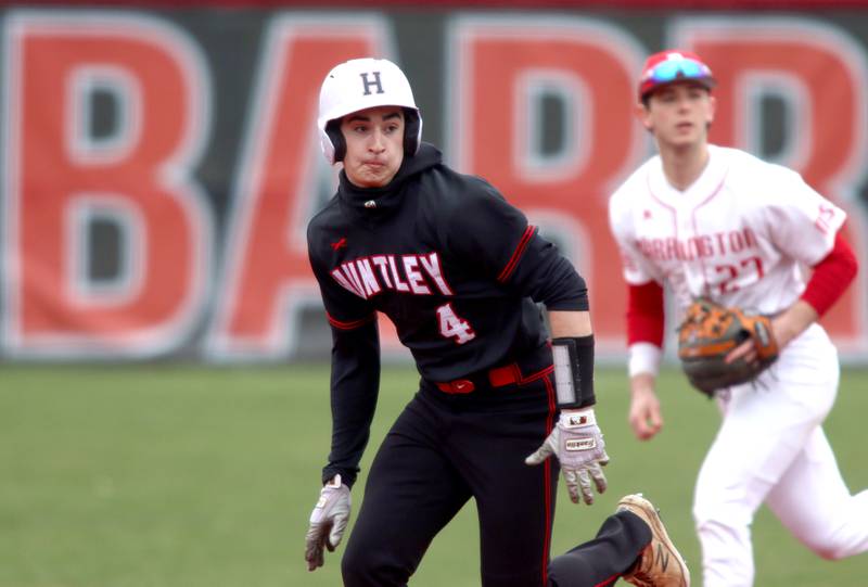 Huntley’s Colby Ashenbach races to third base as Barrington’s Julian Ashley-Friedman follows the play in varsity baseball at Barrington Saturday.
