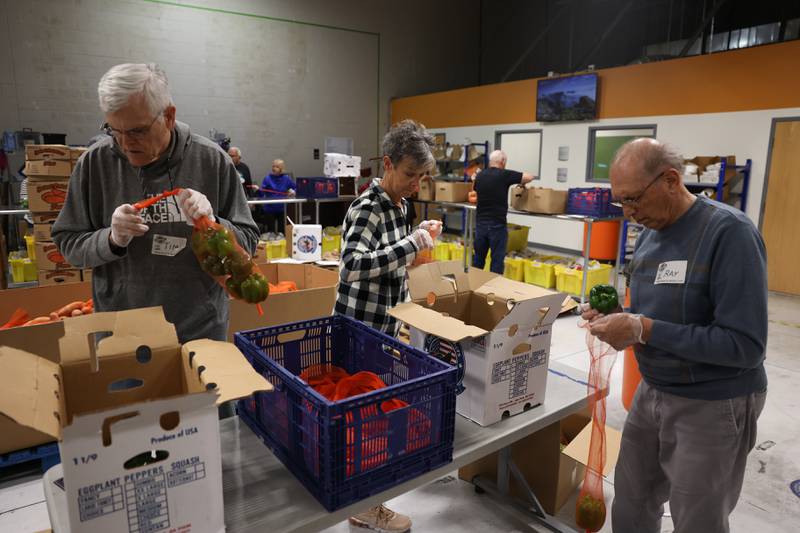 Shorewood volunteers Tim Rhodes, left, Marg Smulski and Ray Paciorek prepare vegetables at the South Suburban Center Food Bank on Tuesday, June 13, 2023 in Joliet.