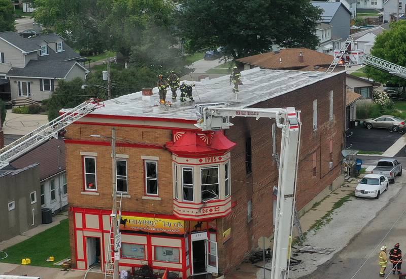 Firefighters use a chainsaw to cut holes into the roof of a building to vet out smoke at 201 North Main Street on Monday, Aug. 14, 2023 in Ladd.