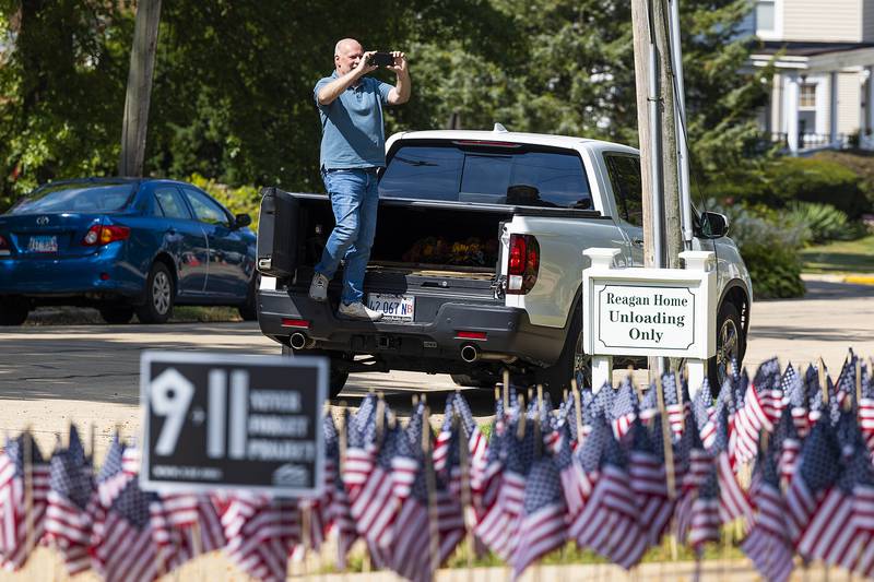 Kevin Marx gets an elevated view Thursday, Sept. 11, 2025, while taking a picture of the flags planted on the grounds of the Reagan Boyhood Home in Dixon. “It’s quite a scene,” said Marx of the striking image of the nearly 3,000 flags that represent the lives lost on 9/11.