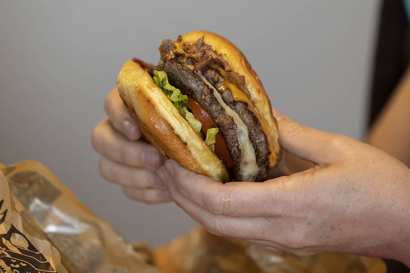 Velinda Cheshire navigates how to dig into the 92 South Peoria burger Monday, Feb. 24, 2025, at Flynnie’s Kitchen.