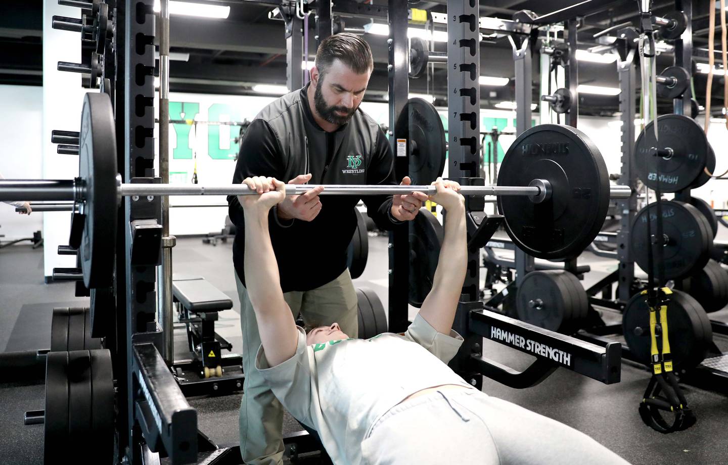 York High School teacher and wrestling coach Nick Metcalf works with senior P.J. Abraham in the school’s weight room.