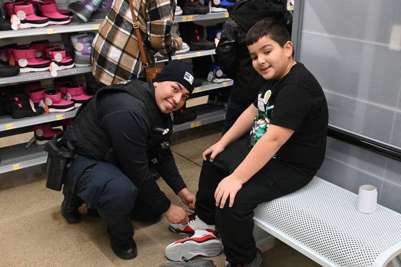 Officer Rodriguez of the Channahon Police Department helps Xavier try on shoes during Grundy County's Heroes and Helpers event on Saturday.