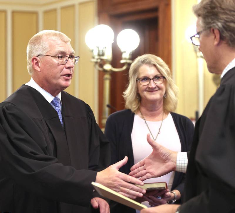Judge Philip Montgomery shakes hands with Judge Bradley Waller after being sworn in as a circuit court judge for the 23rd Judicial Circuit Court as his wife Lisa Montgomery looks on Friday, July 15, 2022, at the DeKalb County Courthouse in Sycamore.
