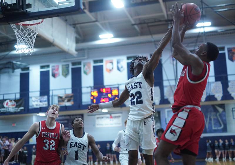 Oswego East's Jehvion Starwood (22) blocks a shot against Yorkville's Dayvion Johnson (3) during a basketball game at Oswego East High School on Friday, Dec 8, 2023.