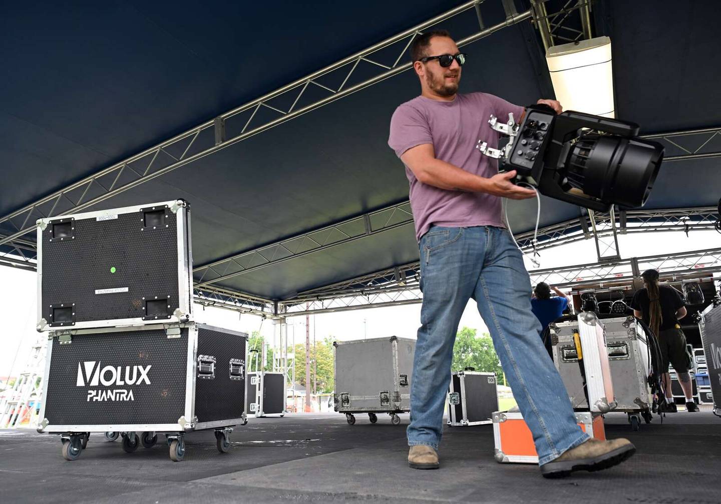 Zack Corp of Diversified Audio Group Inc. carries a stage light during setup for Frontier Days on Tuesday. 7th heaven, a popular rock band on the suburban summer festival circuit, headlines the main stage at 8 p.m. Wednesday.