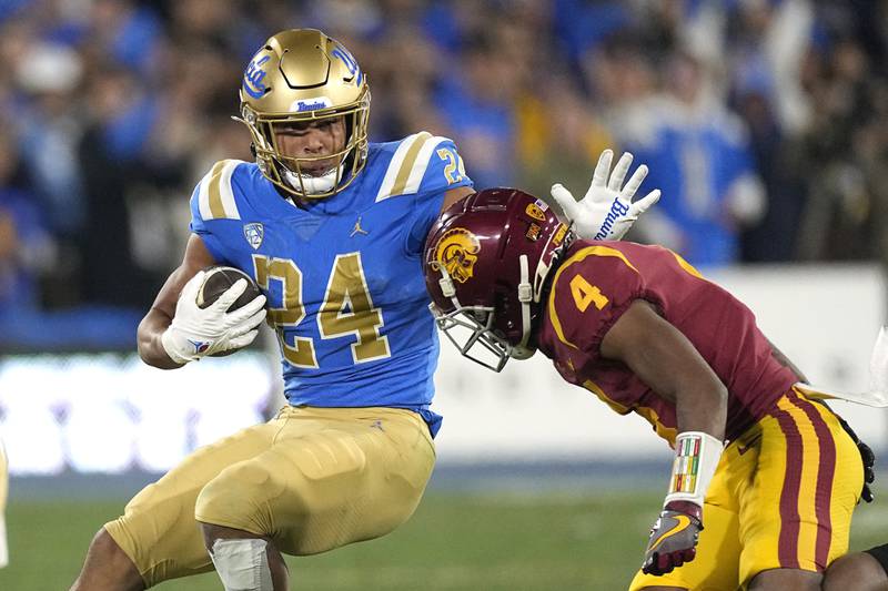 UCLA running back Zach Charbonnet fends off Southern California defensive back Max Williams during a 2022 game in Pasadena, Calif.