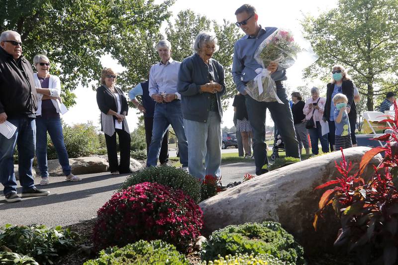 Andy Teegen of NRB Land, LLC, holds a bouquet of flower for Lorraine "Rayne" Gerhardt, 101, during a ceremony in her honor Thursday, Sept. 30, 2021, with friends, family, and colleagues along a walking path inside the Stonewater subdivision in Wonder Lake. Gerhardt was instrumental in the subdivision's approval.