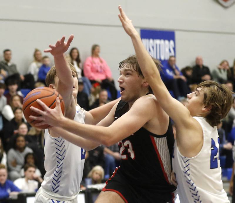 Huntley's Ethan Blackmore splits the defense of Burlington Central's Jacob Johnson (left)  and Bennek Braden (right) as he drives to the basket during a Fox Valley Conference boys basketball game on Friday, Dec. 15, 2023, at Burlington Central High School.