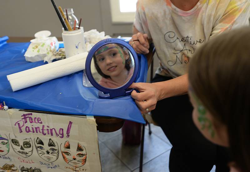 Vivienne Walsh of Downers Grove reacts to seeing her witch face painting during the Last Straw event held at the Gregg House Museum Sunday Oct. 2, 2022.