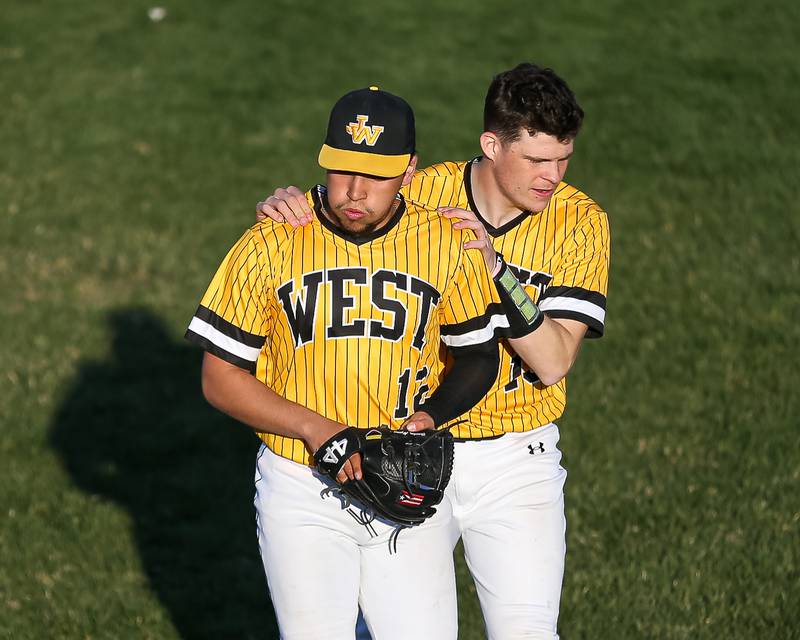 Joliet West's Brandon Alzamora (12) is congratulated by Joe Lukancic (19) after getting the last batter out in their win over  Oswego East.  April 10, 2023.