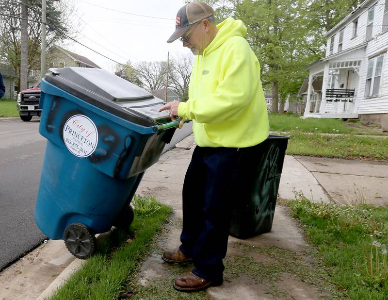 Mike Carrow streets and sanitation employee, wheels a new garbage tote over the curb in front of a home on First Street on Monday, April 29, 2024 in Princeton.