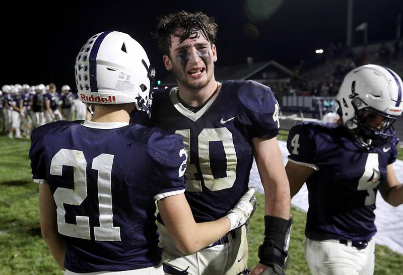 Cary-Grove's Logan Abrams (center) receives a hug from Tanner Hurley (left) as they leave the field after loosing to Belvidere North in an  IHSA Class 5A quarterfinal playoff football game on Friday, November 14, 2025, at Cary-Grove High School, in Cary.