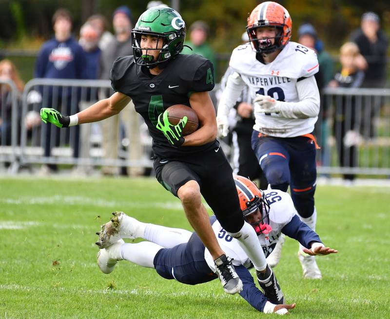 Glenbard West's Mason Ellens (4) escapes Naperville North tackler Zion Lee (58) on a punt return during an IHSA Class 8A playoff game on Oct. 28, 2023 at Glenbard West High School in Glen Ellyn.