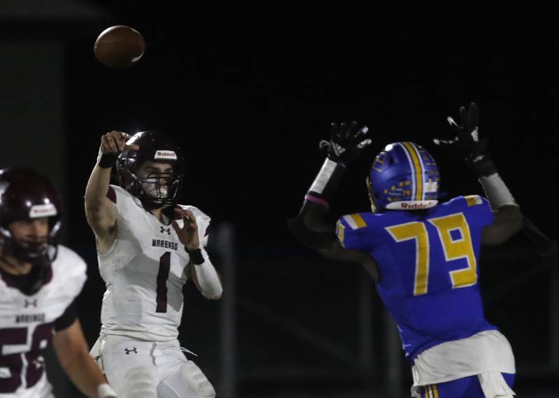 Marengo's David Lopez passes the ball over a rushing Johnsburg's Chinedu Ameachi during a Kishwaukee River Conference football game on Friday, Oct. 4, 2024, at Johnsburg High School.