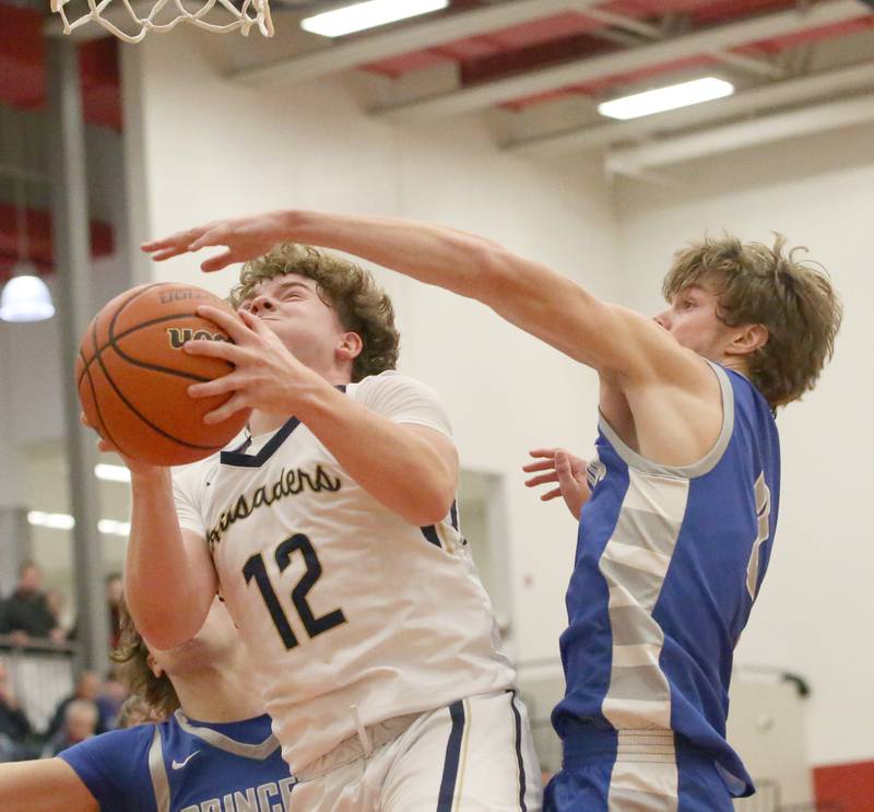 Marquette's Krew Bond (left) struggles to shoot a shot under the hoop as Princeton's Teegan Davis (right) defends during the Colmone Classic tournament on Friday, Dec. 9, 2022 at Hall High School in Spring Valley.