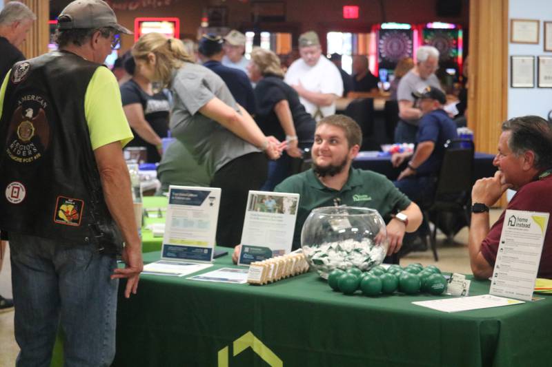 Don Paulsen (left) is greeted Saturday, Aug. 2, 2025, at a booth by Quyler Dahlberg and Rob Mondi (right) of Home Instead Senior Care. It was all part of a veterans awareness fair taking place during Veterans Weekend in Genoa.