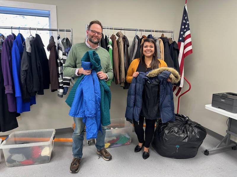 We Care of Grundy County's Eric Fisher (left) accepts the donation of coats from Grundy Bank's Christine Mendez.