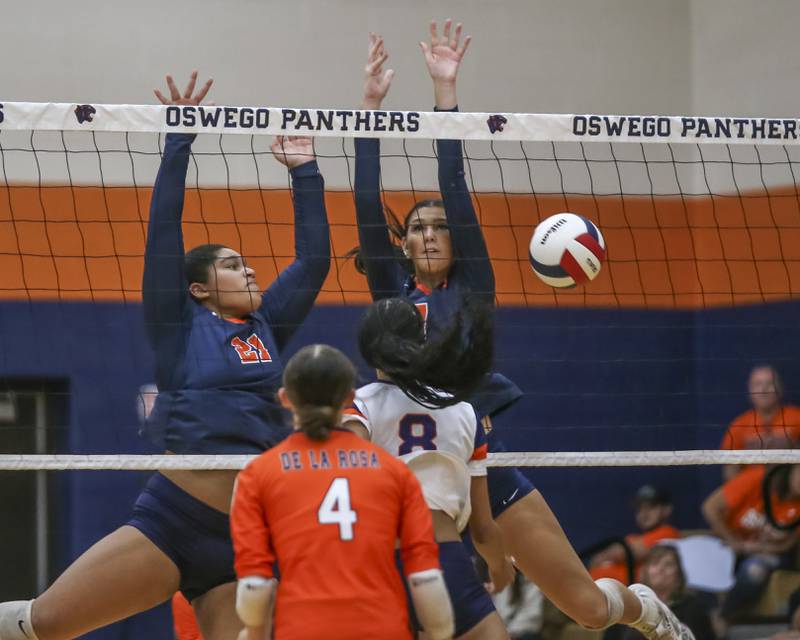 Oswego's Dani Brooks (21) and Hannah Herrick (7) block a ball at the net during volleyball match between Romeoville at Oswego. Oct 16, 2025.