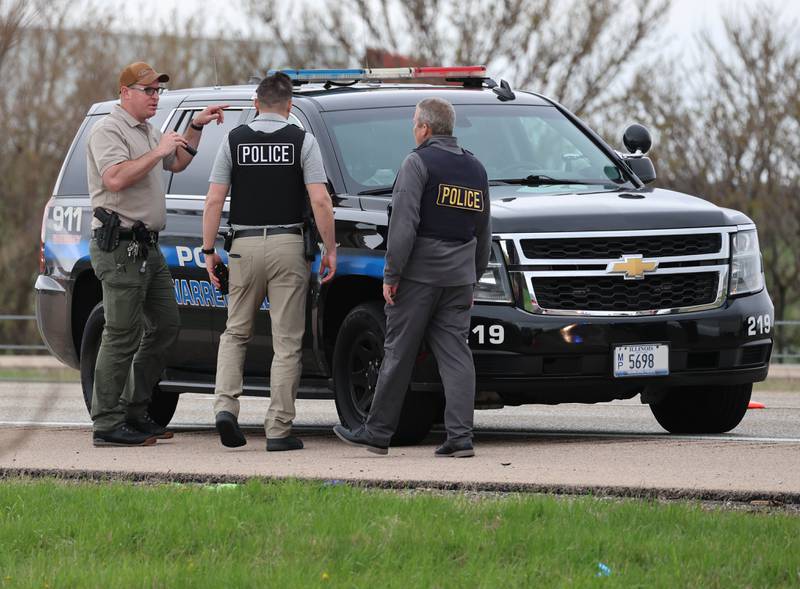 Law enforcement officials look into a Warrenville Police car near a Honda sedan with a shattered window in the westbound lanes of Interstate 88 Monday, April 27, 2026, as they investigate an incident on I-88 just west of Keslinger Road in Maple Park.