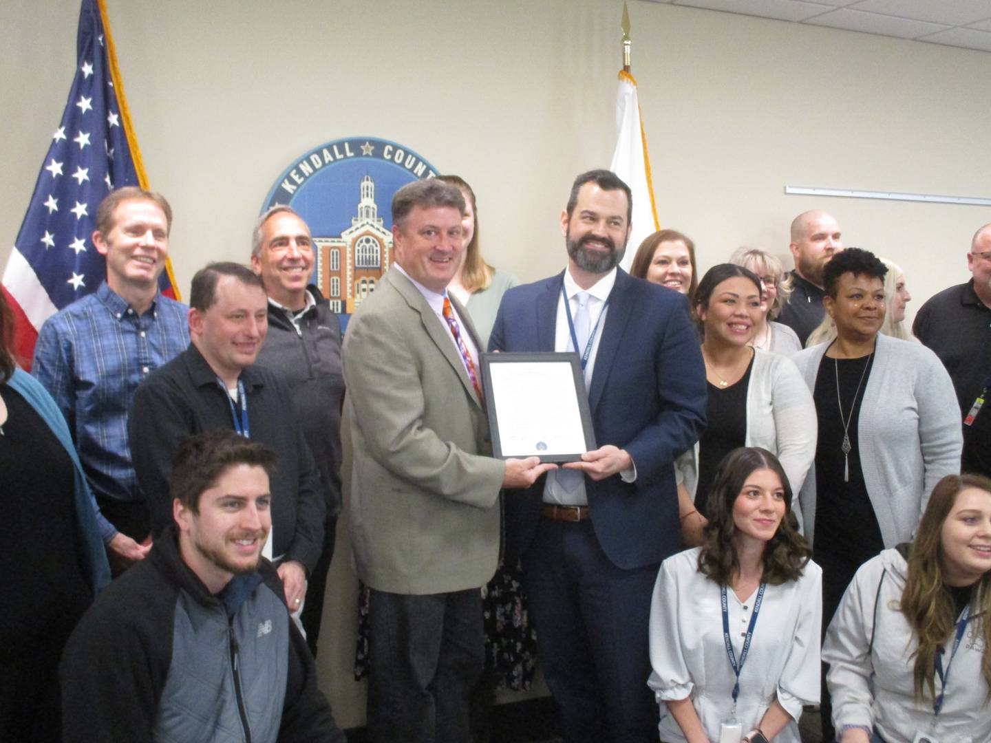 Kendall County Administrator Scott Koeppel, center right, receives a proclamation in his honor from County Board Chairman Matt Kellogg, while surrounded by county employees on April 18, 2023.