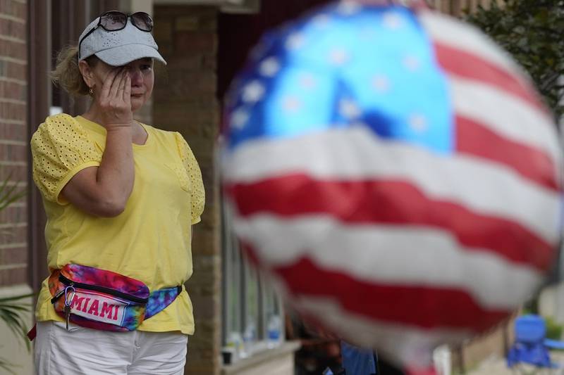 FILE - A woman wipes away tears after a mass shooting at an Independence Day parade that left seven people dead and dozens wounded, in the Chicago suburb Highland Park, July 4, 2022. Violence and mass shootings often surge in the summer months, especially around the Fourth of July, historically one of the deadliest days each year. (AP Photo/Nam Y. Huh, File)