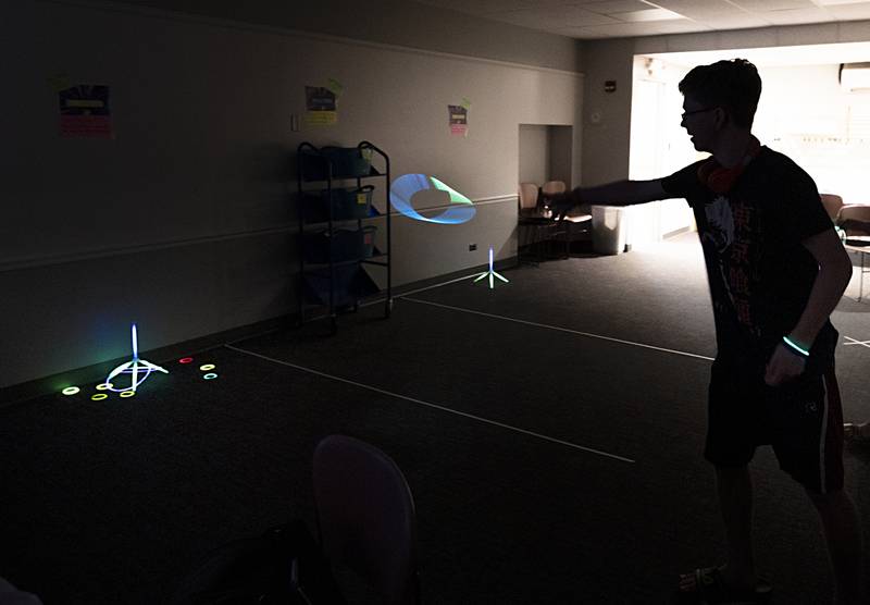 The light were turned off Tuesday, July 16, 2024, at the Dixon Public Library to enhance the look of its young adult glow party. Here, Josh Coss, 17, throws a ring at a target as part of the fun. About once a quarter moving forward, the library will host a teen-based program.