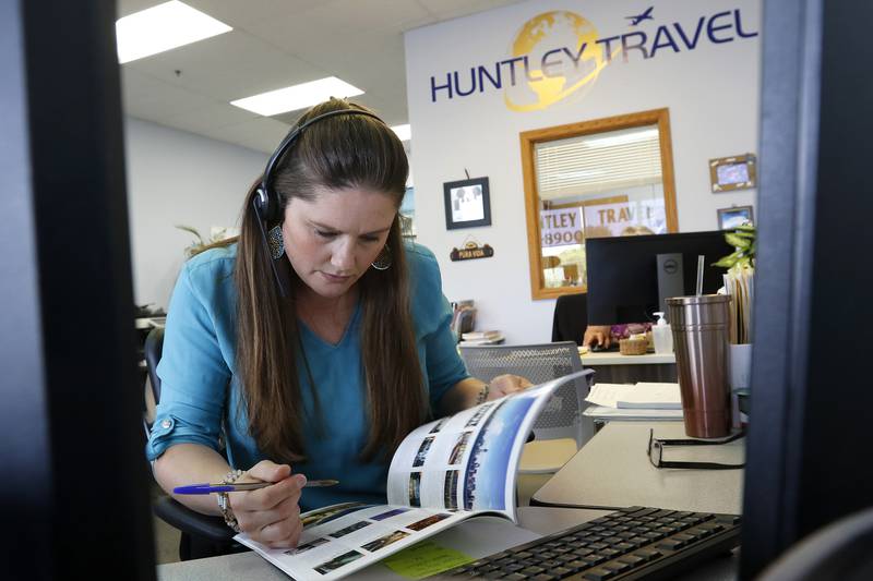 Huntley Travel sales associate Jaime Johnson looks though a travel brochure to pick out suitable options for a client over the phone on Monday, July 19, 2021, in Huntley.  Travel agencies are picking business back up this year as more places reopen their borders to vacationers.