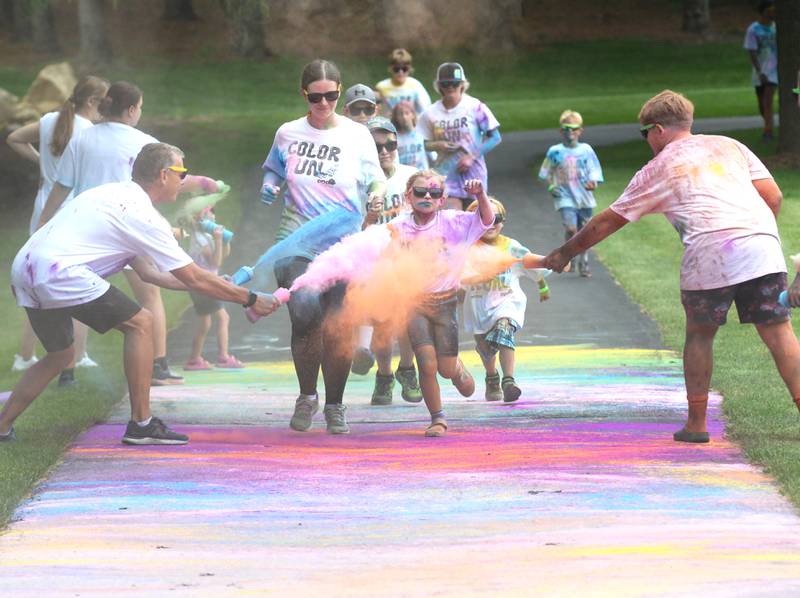 Michelle and Nora Rogers, 7, of Oregon, run through the final color station at the Oregon Park District's color run on Tuesday, July 30, 2024. Runners and walkers got doused with powdered colors as they made their way through the course at Oregon Park West.