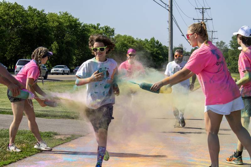 Runners are greeted with clouds of color by volunteers at a color station during CASA DeKalb County's annual 5K Color Run on Saturday, June 3, 2023. According to Jill Olson, executive director for CASA DeKalb County, there were approximately 45 volunteers at the color run.