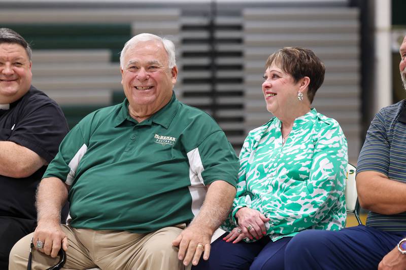 Longtime Bishop McNamara football coach Rich Zinanni, left, smiles and reaches for his wife, Jane, as the crowd applauds for him during the ribbon-cutting ceremony for the new Rich Zinanni Athletic Complex on Thursday, Aug. 21, 2025.
