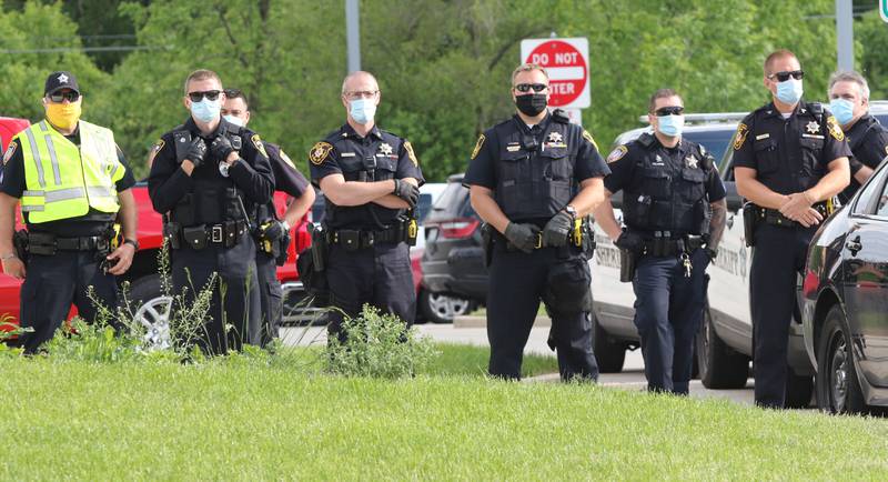 Police from area agencies watch as people protest Monday in front of the DeKalb Police Department. The protest drew about 200 people who were angry about police violence and the recent death of George Floyd who died after a Minneapolis police office knelt on his neck for nearly 10 minutes.