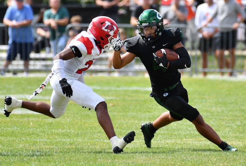 Glenbard West's Julius Ellens (right) tries to elude a Marist tackler after catching a pass during a game on Aug. 26, 2023 at Glenbard West High School in Glen Ellyn.