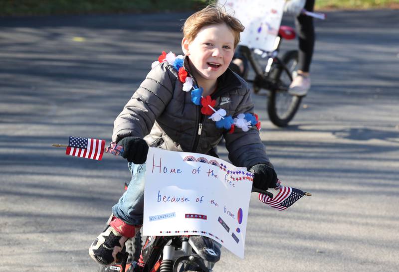 Jaxson Kunkel, 5, from Sycamore, rides in a small parade with his grandma and siblings on Veterans Day, Friday, Nov. 11, 2022, for the veterans at the Grand Victorian assisted living facility in Sycamore. Joann Kunkel read a story in the Midweek that contained a quote from one of the veterans at the facility that lamented the lack of a parade. So she and her grandkids decided to have one for them.