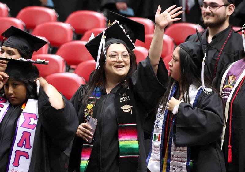A Northern Illinois University candidate for graduation waves to her family as the students are seated during the first of two undergraduate commencement ceremonies Saturday, May 11, 2024, in the Convocation Center at NIU in DeKalb.
