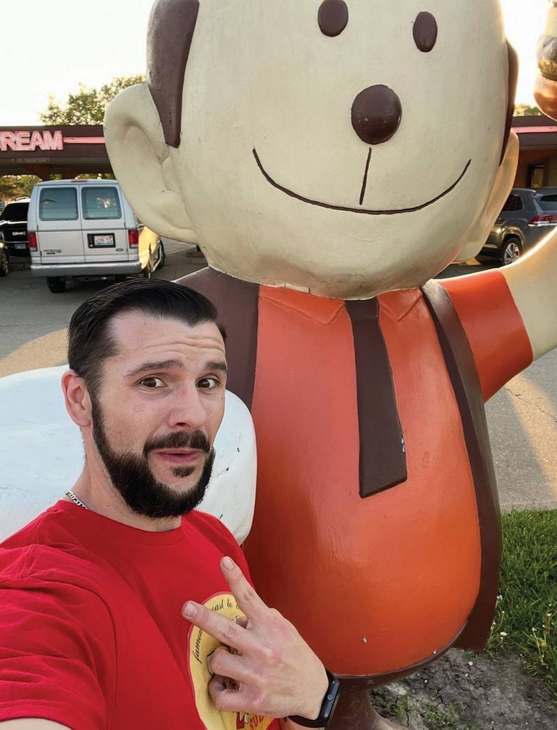Seth "Guse" Ragusa, the social media influencer who creates Grazing Guse restaurant reviews, flashes a peace sign next to the hamburger man statue at The Rootbeer Stand in Oglesby. He signs off from each of his restaurant reviews by saying, "Peace."