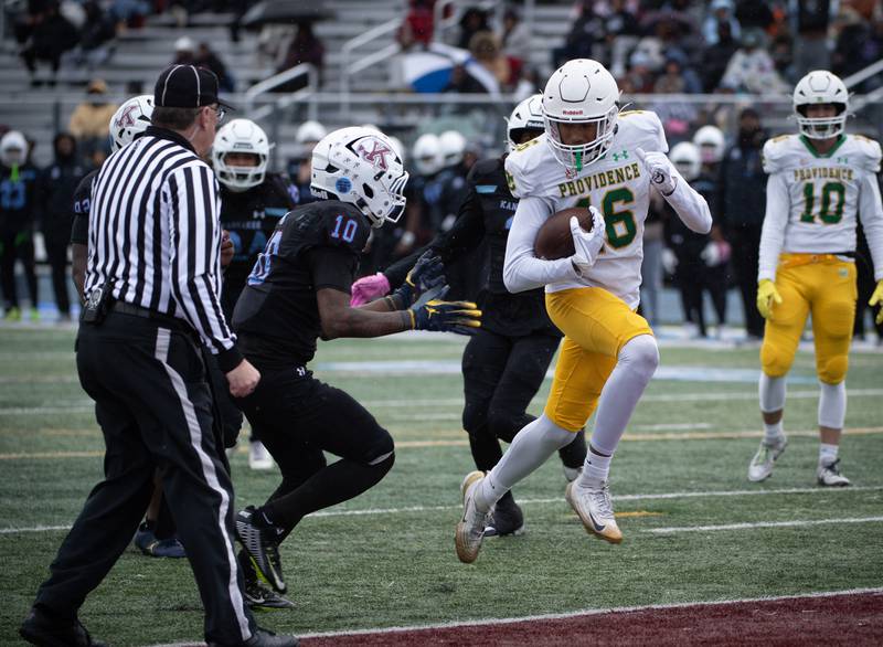 Providence Catholic's DeAngelo Coates, center, carries the ball into the endzone for a touchdown as Kankakee's Caiden Benson, left, defends during a Class 5A playoff game on Saturday, November 8, 2025.